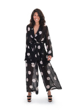 Load image into Gallery viewer, Front full body view of a woman wearing the alembika chiffon dot palazzo pant with a matching chiffon shirt. The pant and shirt is black with white dots. The fabric appears sheer. The pants are wide legged and end right above the ankles.
