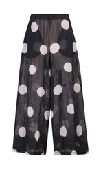 Load image into Gallery viewer, Front view of the alembika chiffon dot palazzo pant. The pant is black with white dots. The fabric appears sheer with a nude slip. The pants are wide legged.
