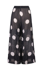 Load image into Gallery viewer, Back view of the alembika chiffon dot palazzo pant. The pant is black with white dots. The fabric appears sheer with a nude slip. The pants are wide legged.
