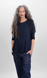 Load image into Gallery viewer, Front top half view of a woman wearing the alembika chiu raglan top. This top is navy with black and navy stripes on the shoulders and long sleeves and black animal print on the body.
