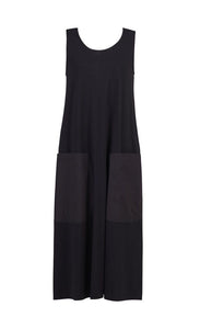 Front view of the alembika cotton tank dress. This long black dress is sleeveless with two large patch pockets on the front and long side slits. 