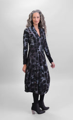 Load image into Gallery viewer, Front full body view of a woman wearing the alembika echo swing dress. This dress is grey, black, and blue tie dye with black dots all over it. It has a v-neck, a balloon skirt, and long sleeves.
