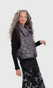 Right side top half view of a woman wearing the alembika ether fina jacket vest in grey over a black long sleeve. This vest is a puffer vest. It features a large folded over collar and a single button closure towards the neck. The hem on the back is black and ribbed.