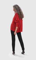 Load image into Gallery viewer, Back full body view of a woman wearing the Alembika Signature Cardigan. This cardigan is red/flame colored. It has long sleeves and a ribbed hem
