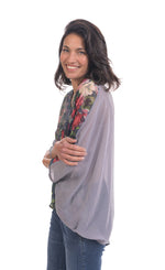 Load image into Gallery viewer, Left side top half view of a woman wearing jeans and the alembika flora top. This top has a floral print on the front, navy and white striping on the back, an oversized fit, and 3/4 length sleeves.
