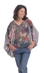 Load image into Gallery viewer, Front top half view of a woman wearing jeans and the alembika flora top. This top has a floral print on the front, an oversized fit, a v-neck, and 3/4 length sleeves.
