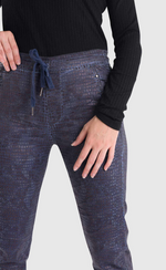 Load image into Gallery viewer, Front bottom half close up view of a woman wearing the alembika iconic stretch jeans in indigo. These pull-on jeans have a drawstring waistband, a straight leg, and two front slant pockets.
