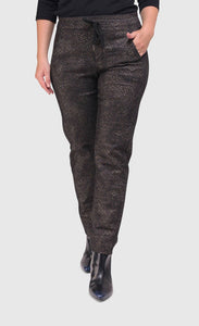 Bottom half front view of a woman wearing the alembika iconic stretch pant in the color sepia. The pant is dark brown/black with a small metallic-like animal print. It also has a drawstring and tie waistband.