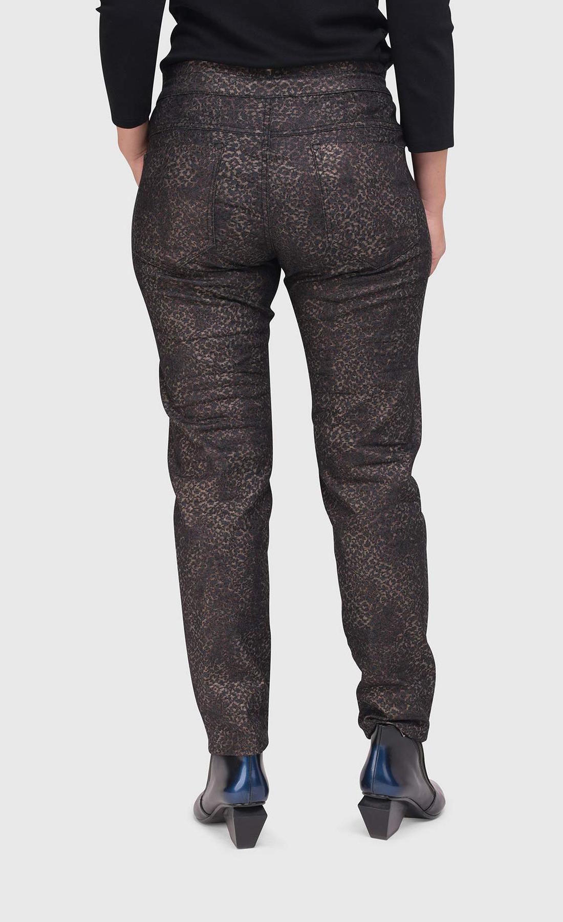 Bottom half back view of a woman wearing the alembika iconic stretch pant in the color sepia. The pant is dark brown/black with a small metallic-like animal print. It also has two back pockets.
