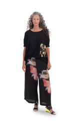 Load image into Gallery viewer, Front full body view of a woman wearing the alembika jersey with garden print block top. This top is black with 3/4 length sleeves, a relaxed fit, and a front green and pink garden print patch.
