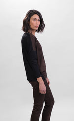 Load image into Gallery viewer, Right side top half view of a woman wearing brown pants and the alembika leopard panel top. This top has a round neck, solid black drop shoulder dolman sleeves, a brown body, and a solid black back.
