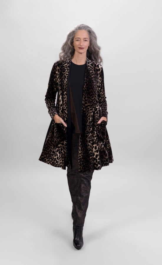Front full body view of a woman wearing the alembika nala velvet jacket in leopard print. This jacket has long sleeves, two pockets, and a draped open front. The jacket sits below the hips.
