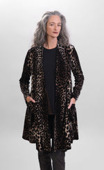 Load image into Gallery viewer, Front top half view of a woman wearing the alembika nala velvet jacket in leopard print. This jacket has long sleeves, two pockets, and a draped open front. The jacket sits below the hips.
