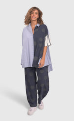 Load image into Gallery viewer, Front full body view of a woman wearing blue pants with green dots and the alembika navy short sleeve shirt. This shirt has blue and white stripes on the front right side and blue with green dots on the left side.
