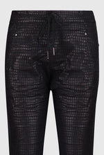 Load image into Gallery viewer, Front close up view of the Alembika Onyx Pant. This pant is black with a shiny snakeskin print on it. It has a drawstring waistband, slim legs, and two slanted side pockets.
