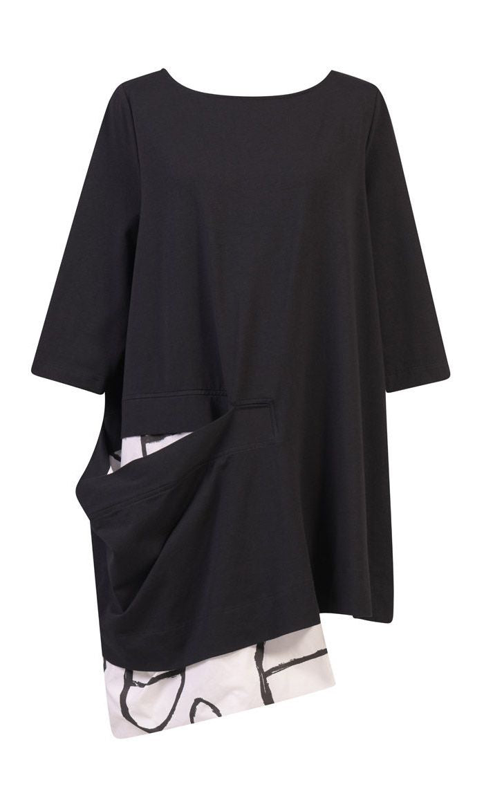Front view of the alembika peek-a-boo pocket tunic. The top has 3/4 length sleeves. It is black with a draped open pocket. The pocket is lined with a white and black circle/capsule like print that hangs down below the hem.