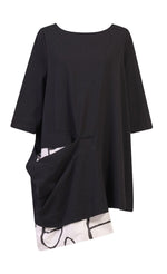 Load image into Gallery viewer, Front view of the alembika peek-a-boo pocket tunic. The top has 3/4 length sleeves. It is black with a draped open pocket. The pocket is lined with a white and black circle/capsule like print that hangs down below the hem.
