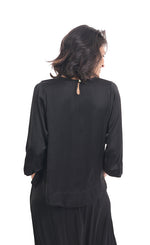 Load image into Gallery viewer, Back top half view of a woman wearing black pants and the alembika lotus top in black. This top a keyhole back and 3/4 length sleeves.
