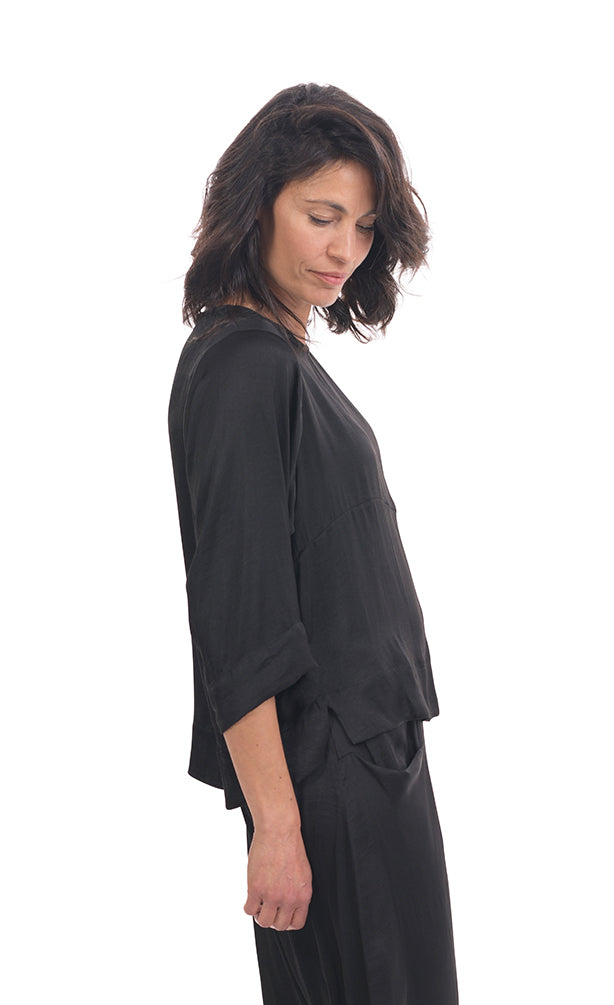 Right side top half view of a woman wearing black pants and the alembika lotus top in black. This top has a round neck and 3/4 length sleeves.