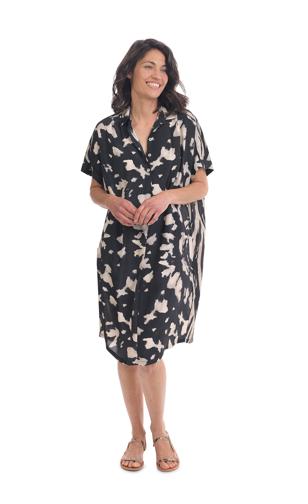 Front full body view of a woman wearing the alembika Speckled Shayna Shirtdress. This shirtdress has a button down front, short sleeves, and a black and white tie-dye print.