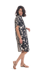 Load image into Gallery viewer, Right side full body view of a woman wearing the alembika Speckled Shayna Shirtdress. This shirtdress has a button down front, short sleeves, and a black and white tie-dye print on the front with a black and white wavy striping print on the back
