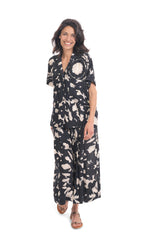 Load image into Gallery viewer, Front full body view of a woman wearing the alembika mandala wide pant and the alembika speckle mandala shirt. This shirt has a black and white mandala tie dye print, a button down front, a shirt collar, a boxy silhouette, and short sleeves. The wide pants have the same print as the top.
