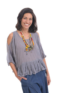 Front top half view of a woman wearing wide jeans and the alembika gingham Rhys Ruffled Blouse. This top has a blue and white plaid print, cold shoulder 3/4 length sleeves, and a ruffled hem.