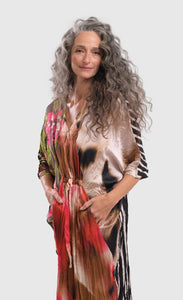 Front left side top half view of a woman wearing the alembika skye caftan butterfly dress. This dress has pink flowers over a brown backdrop on the right side, a pink and brown tie dye print in the center, a beige and brown tie dye print on the left side, and a black and white striped print on the back.