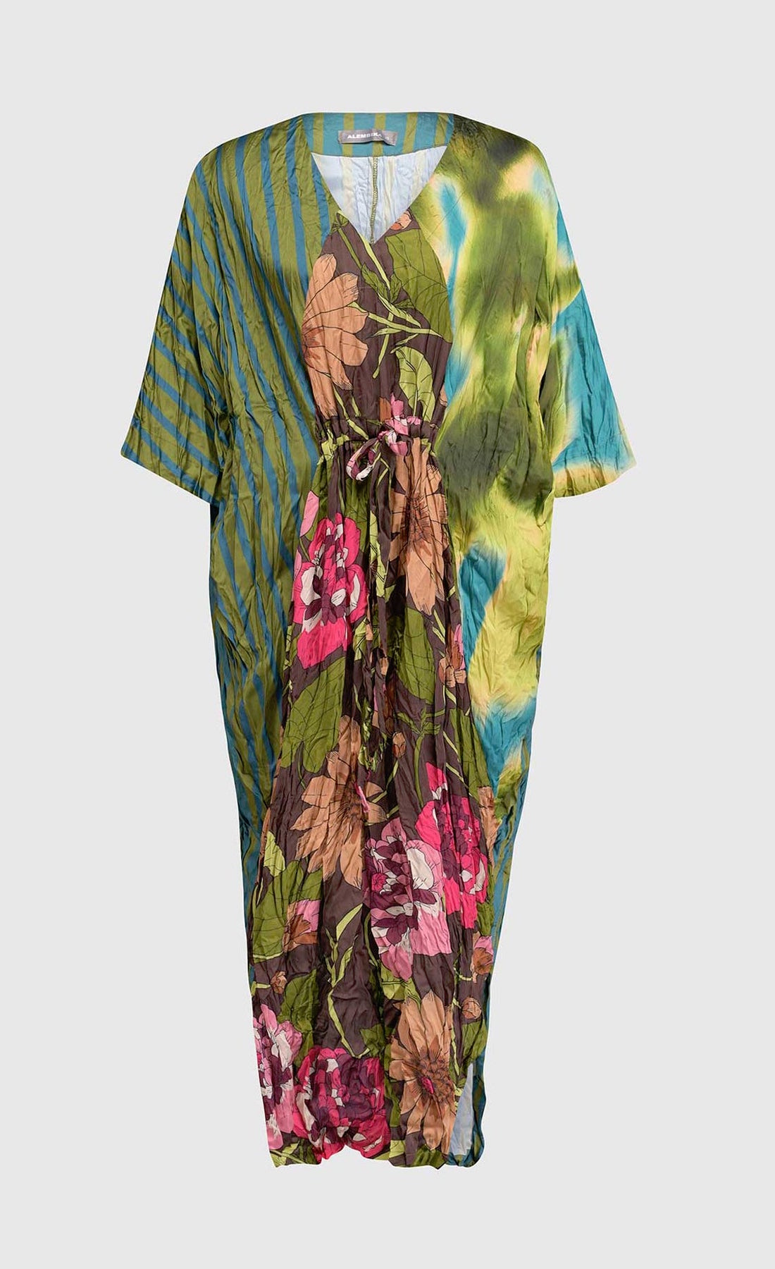 Front full view of a the alembika skye caftan dress in the color aquamarine. This dress has green, yellow, and blue tie dye on the left side, blue and green stripes on the right side and back, and pink flowers on a brown backdrop down the center of the front. The center of the front of the dress is tied to bring the waist in.