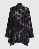 Load image into Gallery viewer, Back view of the alembika swing top in smoke. This top is black, grey, and blue tie dye with black dots all over it. The top has a mock neck, long sleeves, and a wide flowy silhouette with a stepped hem.

