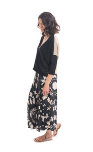 Left side full body view of a woman wearing the alembika speckle mandala wide pant and the alembika colorblock top in black multi. The pant has a tie dye black and white print and wide legs.