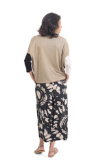Load image into Gallery viewer, Back full body view of a woman wearing the alembika speckle mandala wide pant and the alembika colorblock top in black multi. The pant has a tie dye black and white print and wide legs.
