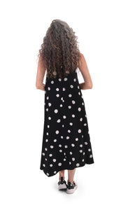 Back full body view of a woman wearing the alembika Lia Spotted Jersey Hi-Low Maxi Dress. This sleeveless dress is black with white spiral circles all over it.  The back has an asymmetrical, longer hem.