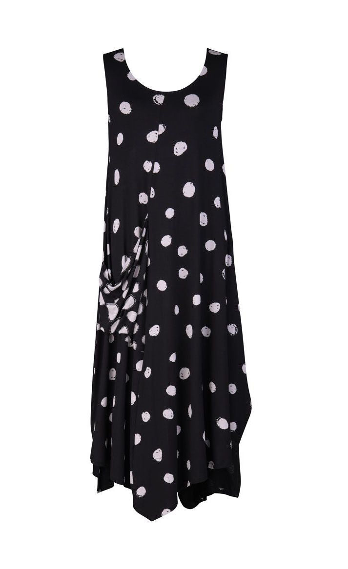 Front view of the alembika Lia Spotted Jersey Hi-Low Maxi Dress. This sleeveless dress is black with white spiral circles all over it. The front has a scoop neck and a front, right-sided draped pocket. The hem is asymmetrical.