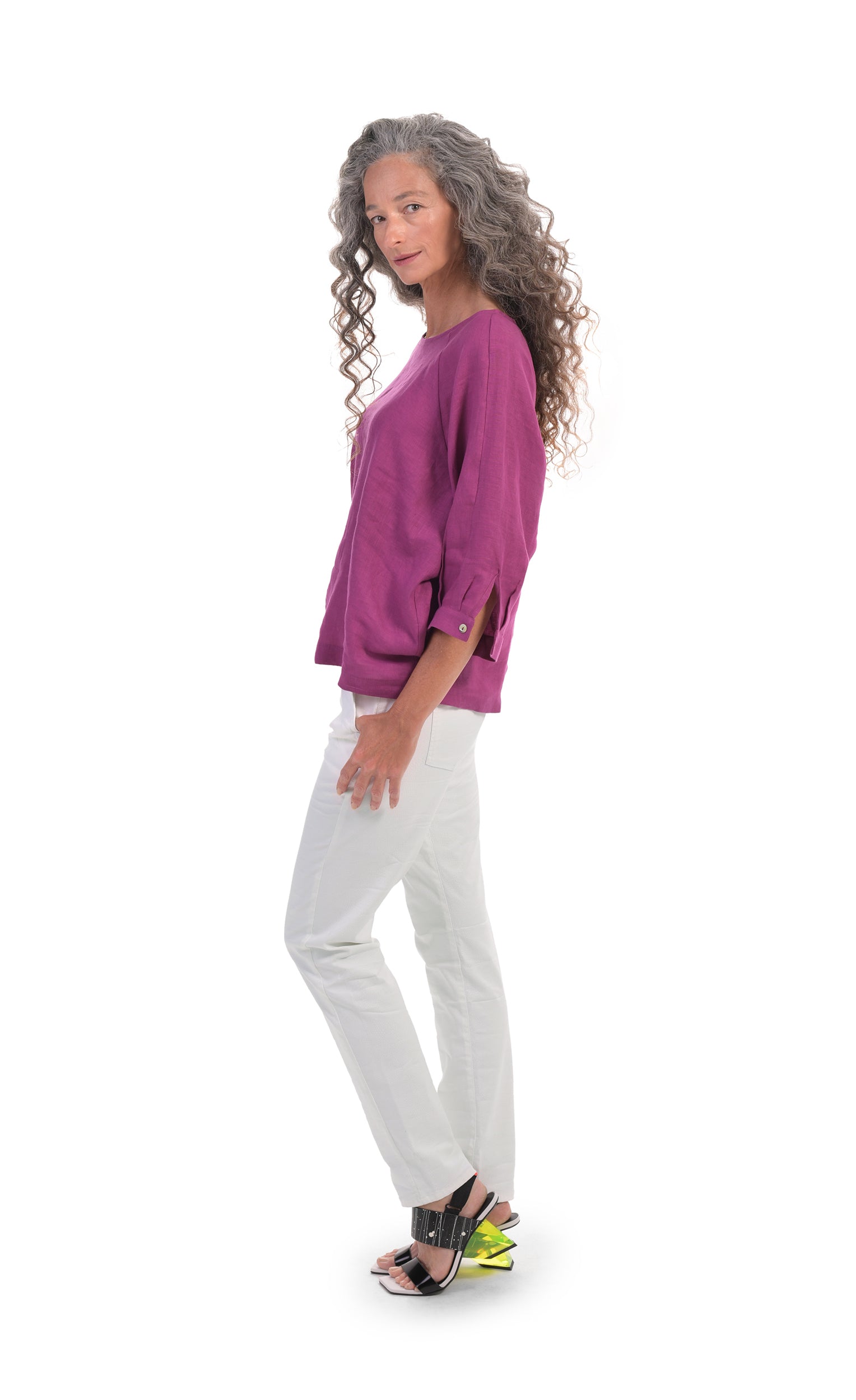 Left sided, full body view of a woman wearing a pink top and the alembika stretch denim pant. This pant is white with two front slant pockets. The pants have a relaxed skinny silhouette.