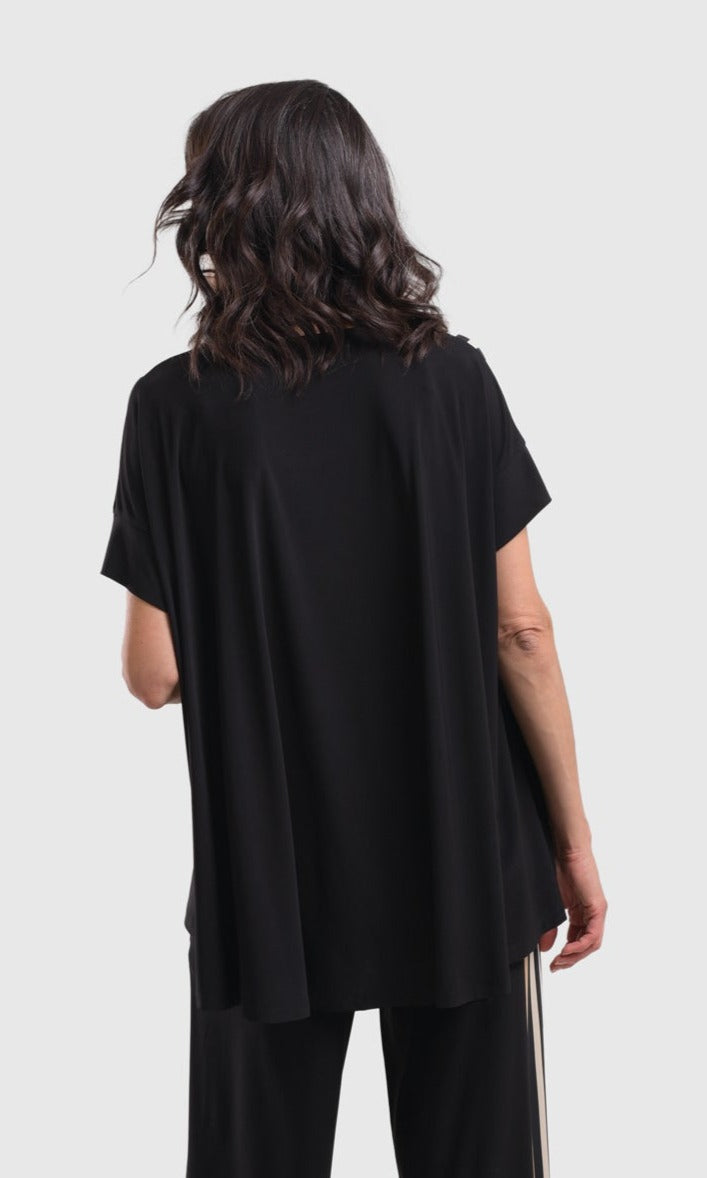 Back top half view of a woman wearing the alembika sunrise stripes swing top. This top has a round neck and short sleeves. the back is solid black.