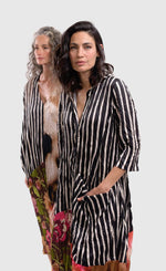 Load image into Gallery viewer, Front top half view of a woman wearing the alembika sunset wonderful dress. This dress has a button down front, black and white striped print and a floral printed bottom. The dress has 3/4 length sleeves.
