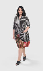 Load image into Gallery viewer, Front full body view of a woman wearing the alembika sunset wonderful dress. This dress has a button down front black and white striped print and a floral printed bottom. The dress has 3/4 length sleeves and a front draped pocket.
