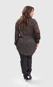 Back full body view of a woman wearing sepia alembika pants and the alembika talia russet blouse. This long sleeved blouse has a button down front, a stand collar, and a mix of different prints that are brown, black, and white.