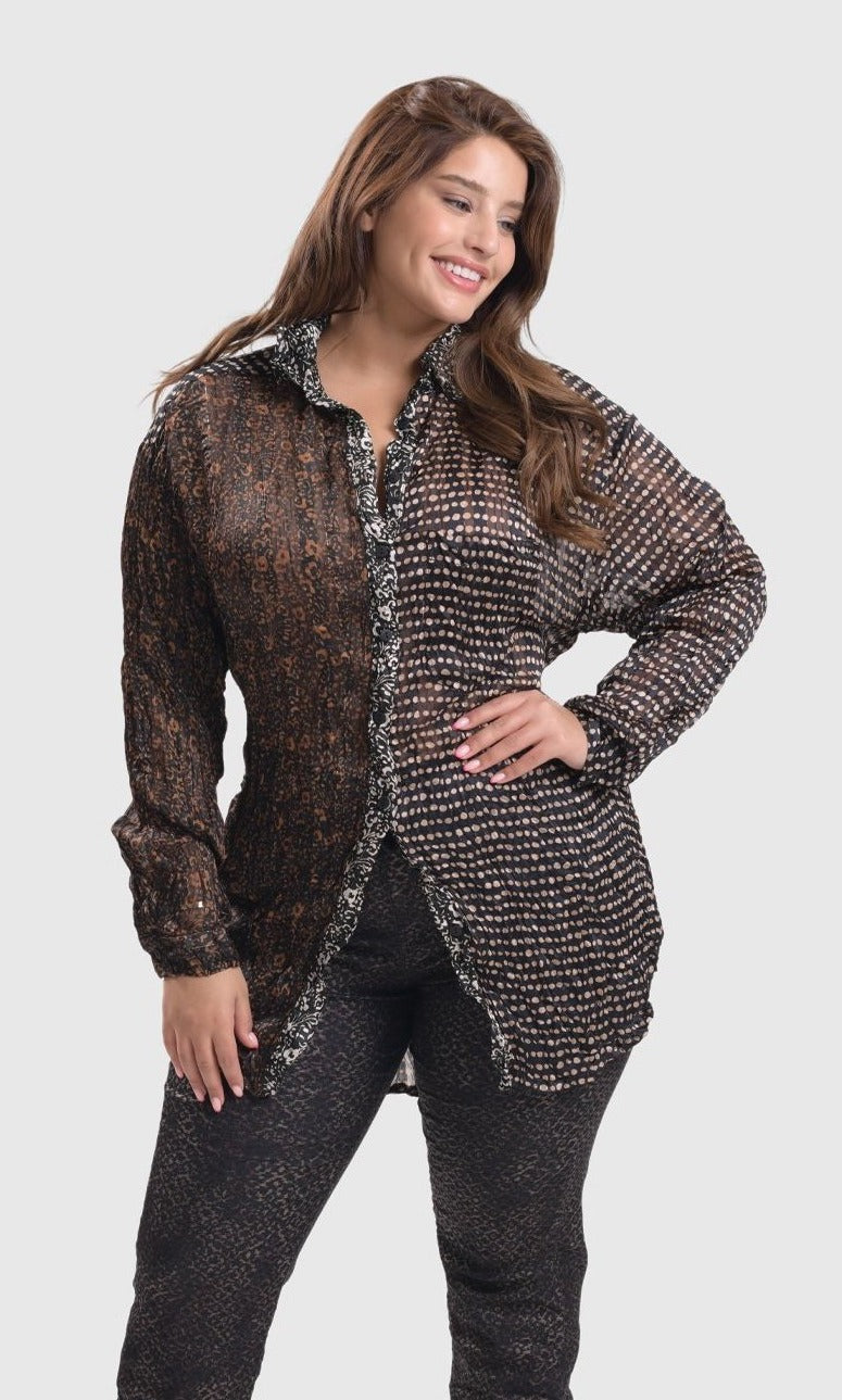 Front full body view of a woman wearing sepia alembika pants and the alembika talia russet blouse. This long sleeved blouse has a button down front, a stand collar, and a mix of different prints that are brown, black, and white.