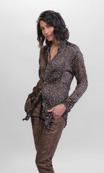 Load image into Gallery viewer, Front top half view of a woman wearing brown alembika pants and the alembika talia russet blouse. This long sleeved blouse has a button down front, a stand collar, and a mix of different prints that are brown, black, and white.
