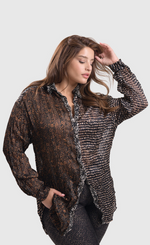Load image into Gallery viewer, Front top half view of a woman wearing sepia alembika pants and the alembika talia russet blouse. This long sleeved blouse has a button down front, a stand collar, and a mix of different prints that are brown, black, and white.
