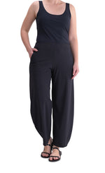 Load image into Gallery viewer, Front full body view of a woman wearing the Alembika Riding Pant. Her hand is in the right pocket. This pant is black with wide legs that slightly taper in at the bottom.
