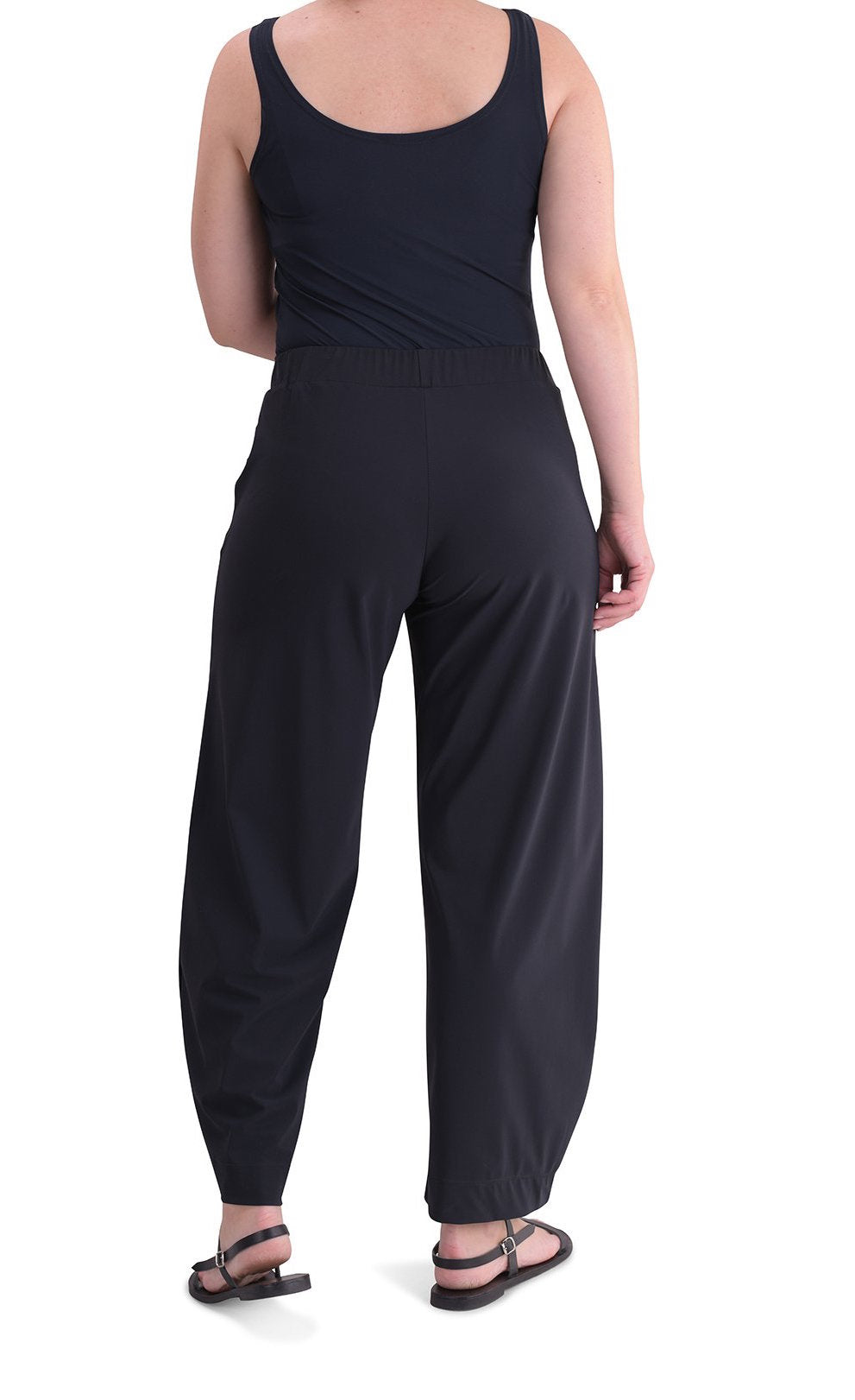 Back full body view of a woman wearing the Alembika Riding Pant. This pant is black with wide legs that slightly taper in at the bottom.