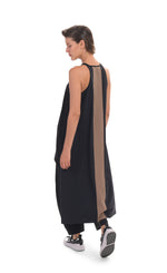 Load image into Gallery viewer, Back, full body view of a woman wearing the alembika tekbika high low top with the alembika tekbika riding pant. The black top is sleeveless with a t-back. The back of the top has a large brown panel running down the center and the hem comes down to just above the ankles.
