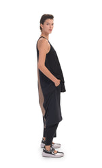 Load image into Gallery viewer, Right side, full body view of a woman wearing the alembika tekbika high low top with the alembika tekbika riding pant. This black top is sleeveless. The back of the top has a large brown panel running down the center and the hem comes down to just above the ankles.
