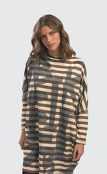 Load image into Gallery viewer, Front top half view of a woman wearing the Alembika Urban Clustur Cocoon Dress. This dress is cream and brown striped with a gray graffiti print all over it. The dress has a cocoon shape that tapers in at the knees. It has drop shoulder, long dolman sleeves and a mock neck.
