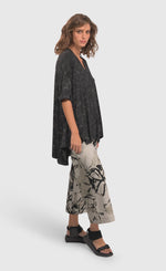 Load image into Gallery viewer, Right side full body view of a woman wearing an alembika marble top and the alembika urban sketch go to pant. This pant is grey white with black and dark grey scribbles all over it. The pant has a cropped cut, and wide legs.
