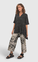 Load image into Gallery viewer, Front full body view of a woman wearing an alembika marble top and the alembika urban sketch go to pant. This pant is grey white with black and dark grey scribbles all over it. The pant has a cropped cut, and wide legs.
