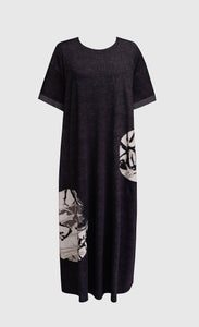 Front view of a the alembika urban moon maxi dress. This dress is dark grey with two patch circles on the bottom 2/3s of the dress. These circles are white/grey with a scribble print on them. The relaxed dress sits just above the ankles and has elbow length sleeves.